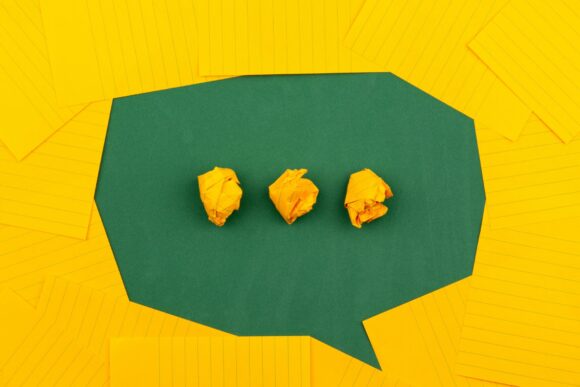 yellow and green paper form a speech bubble with three dots